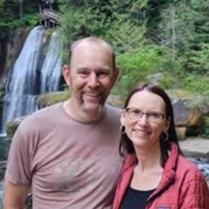 Ben Whitcomb with his wife Janet standing together in front of a waterfall.