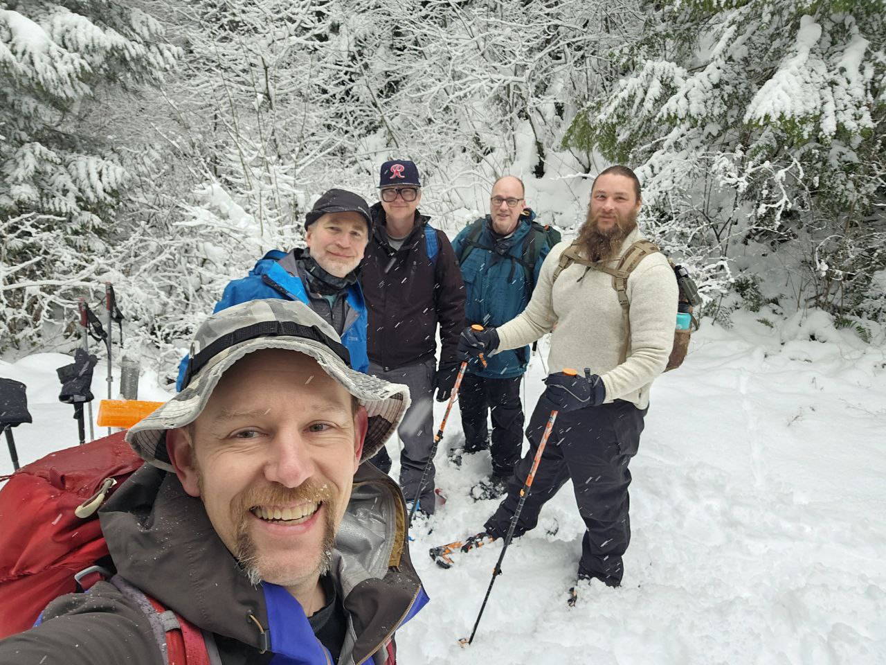 Five men from Calvary Chapel Thunder Mountain snowshoeing together in a snow-covered forest.